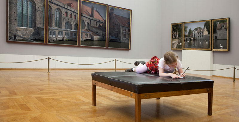 Ein Mädchen macht sich auf einer Sitzbank in einem Museum Notizen.