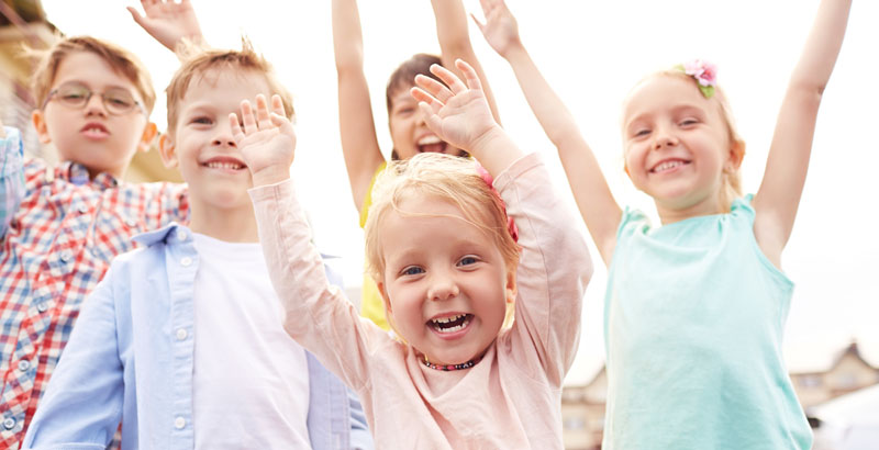 Eine Gruppe Kinder reißt jubelnd die Arme in die Luft. 