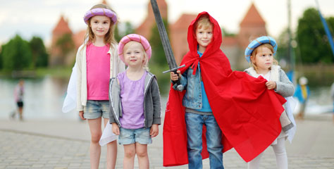 Vier Kinder, der Junge trägt Schutz-Cape und Schwert. 